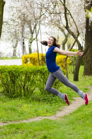 A happy young woman jumping in the parkの写真素材