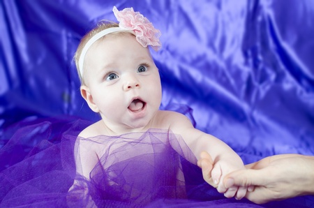 A parent holding baby girl with mauve satin backgroundの写真素材