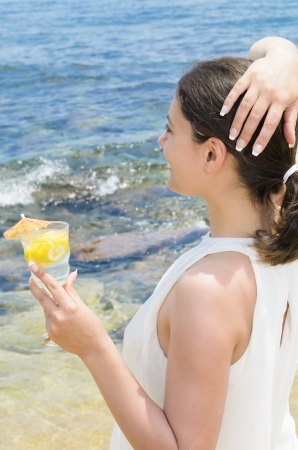 Beautiful woman holding a cocktail on beachの写真素材