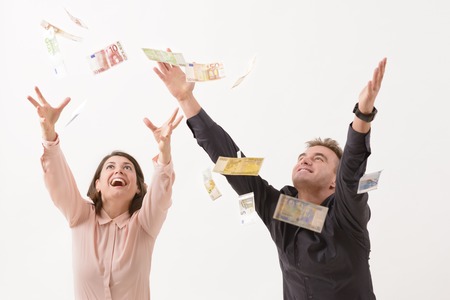 Young couple catching falling moneyの写真素材