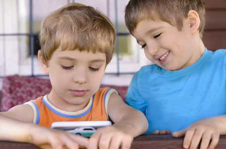 Happy kids playing with a smart phoneの写真素材