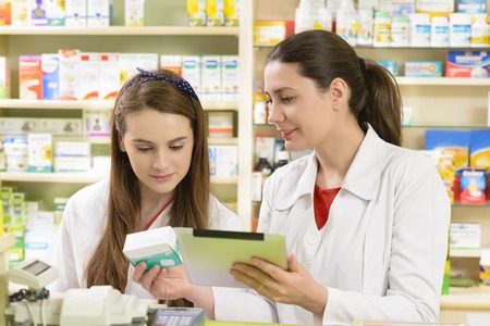 Two young female pharmacist in a drugstore working on a tablet pcの写真素材