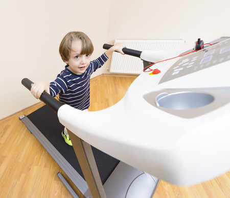 Cute boy running treadmill at homeの写真素材