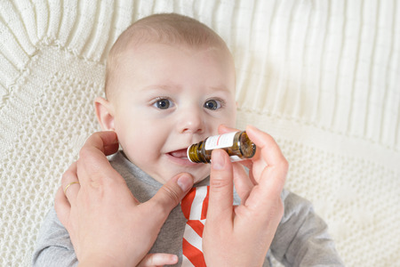 Cute baby gets medicine from a little bottleの写真素材