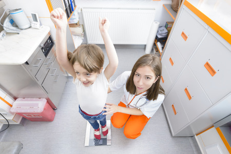 Happy kid on a weighing enjoying his growth at doctor visitの写真素材