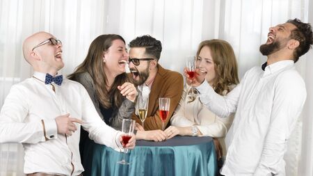 Friends laughing hilarious in a bar, holding glasses of wineの写真素材