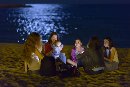 Group o young people spending the night on beach in the moonlightの写真素材