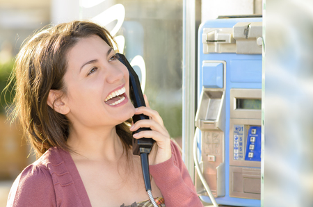 A happy woman talking at a public telephoneの写真素材