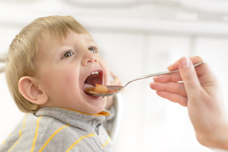 Baby boy fed by his mom at homeの写真素材
