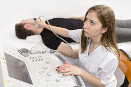 Man being checked for thyroid at ultrasound device in a hospitalの写真素材