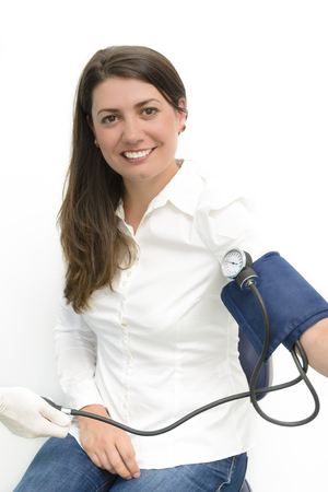 Beautiful young woman using blood pressure measurement device sphygmomanometerの写真素材
