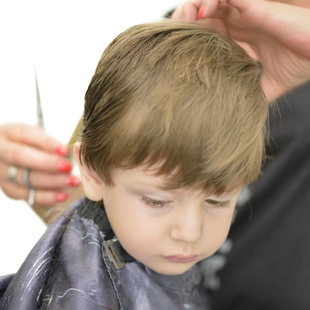 Cute serious little boy at barbershopの写真素材