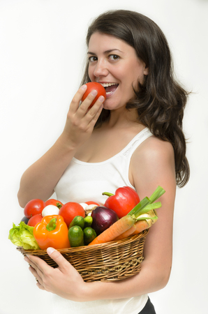 Beautiful young woman holding a basket full of vegetablesの写真素材