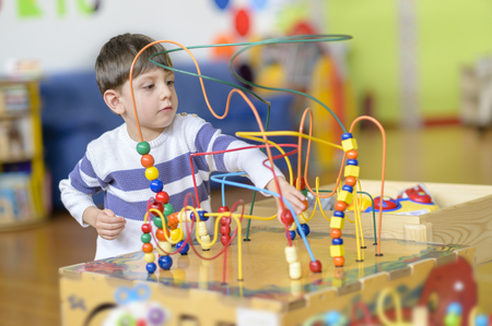 Cute little boy playing at kindergarten with marble balls toyの写真素材