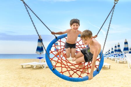 Funny kids swinging on beach, sunny summer dayの写真素材