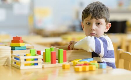Cute little boy playing alone at kindergarten with construction toyの写真素材