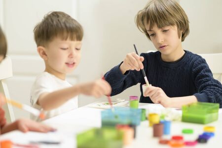 Cute funny kids doing their craft, painting at kindergartenの写真素材