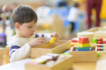 Cute little boy playing alone at kindergarten with construction toyの写真素材