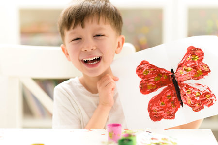 Proud kid showing his buterfly paint craft at kindergartenの写真素材