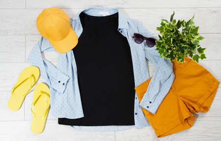 Black T-shirt, denim shirt, sunglasses, cap and shorts top view