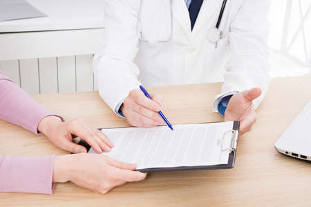 doctor discusses with female patient medical contract at the clinic, medical insuranceの写真素材