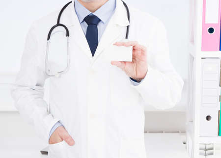 Doctor showing his business card, Medical concept, medical insurance, man in white uniform. Copy...