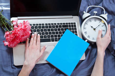 Hands working on laptop in bed top view, female blogger life conceptの写真素材