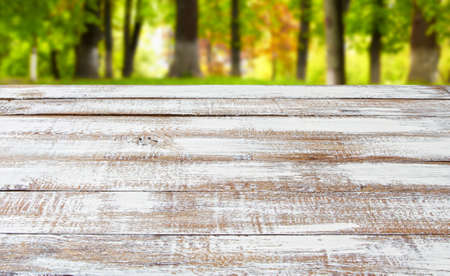 empty wooden desk on blurred park backgroundの写真素材