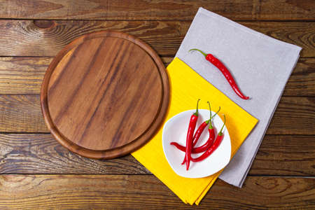 top view - empty pizza desk board on wood table with chili pepper, mock up isolated on whiteの写真素材