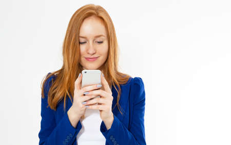 Pretty redhead girl with phone smiling isolated on white background. Young foxy female in business...