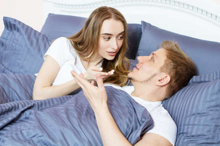 Happy young couple discussing something in bed in the bedroom in the morning.