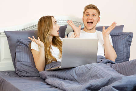 Large portrait: Young lovely couple on bed, morning bedroom. Happy loving couple in the bedroom in...