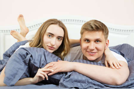 Young happy loving couple in the bed and hold each other's hand