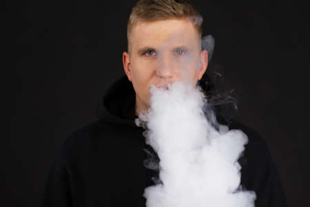 Men smoke an electronic cigarette on the dark background. selective focus