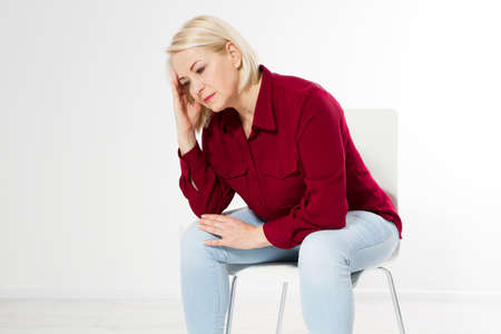 Middle age woman head pain migraine, Beautiful sad middle-aged woman sits on a chair, she has a headacheの写真素材