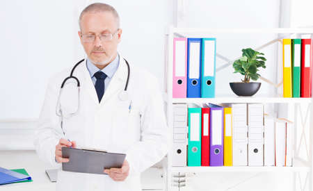 doctor writes something in folder in the clinic officeの写真素材