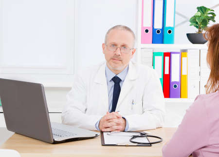 Portrait of senior doctor in medical office.Man in white uniform. Medical insurance. Copy space. Quality medicine concept. Copy spaceの写真素材