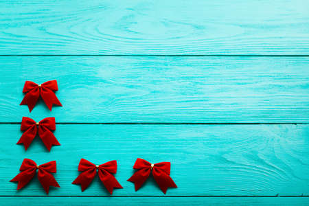 Frame of red bows on blue wooden background with copy space. top view