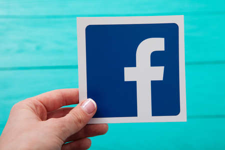 KIEV, UKRAINE - MARCH 10, 2017. Facebook logotype printed on paper. Woman holding in hand Facebook logo. Facebook popular social networking service. selective focus.のeditorial素材