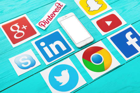 KIEV, UKRAINE - MARCH 10, 2017. Collection of popular social media logos printed on paper: YouTube,Facebook, Twitter, Google Plus, Yahoo, Linkedin, Dropbox and like on blue wooden background.のeditorial素材