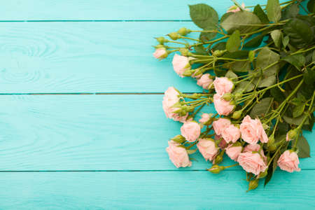 Frame of colorful roses on blue wooden background. Top view and selective focusの写真素材