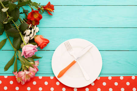 Festive dinner and roses on blue wooden background. top view. Mock up. Flowersの写真素材