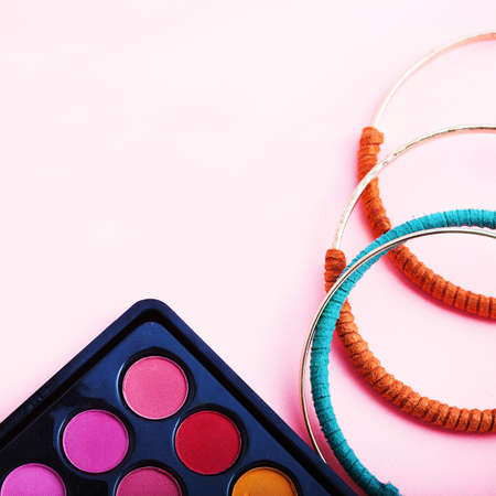 Braclets and makeup shadows on pink background. top viewの写真素材