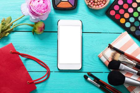 Frame of cosmetics and blank mobile screen on blue wooden background. top view and copy spaceの写真素材