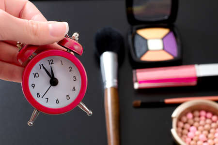 Concept cropped image with cosmetic and make up products. Quick make up. Red retro clock. selective focusの写真素材