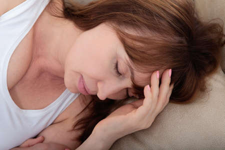daytime sleep. Middle age woman sleeping on bed in modern apartment. home background. copy space and mock up. Menopauseの写真素材