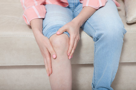 Cropped image of female sore knee. woman at home background. copy space and mock up.の写真素材