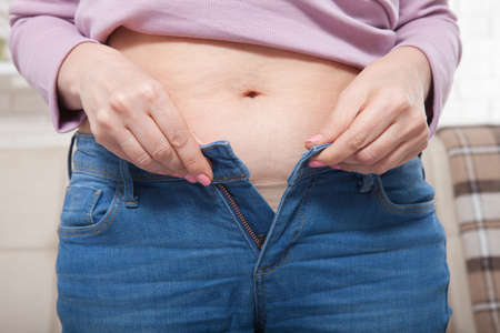 Macro picture of female bodypart . Belly of a beautiful woman on home background.