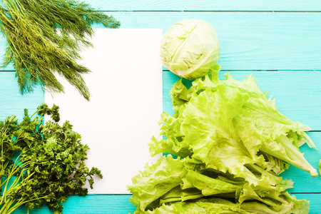 Cabbage and lettuce with recipe paper and copy space on blue wooden table.の写真素材
