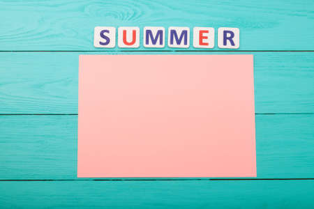 Word summer and paper with copy space on blue wooden background. top view